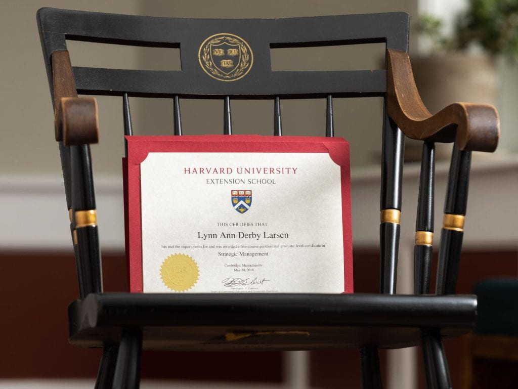 Wooden chair with Harvard Veritas shield and Extension School certification leaning on the chair.